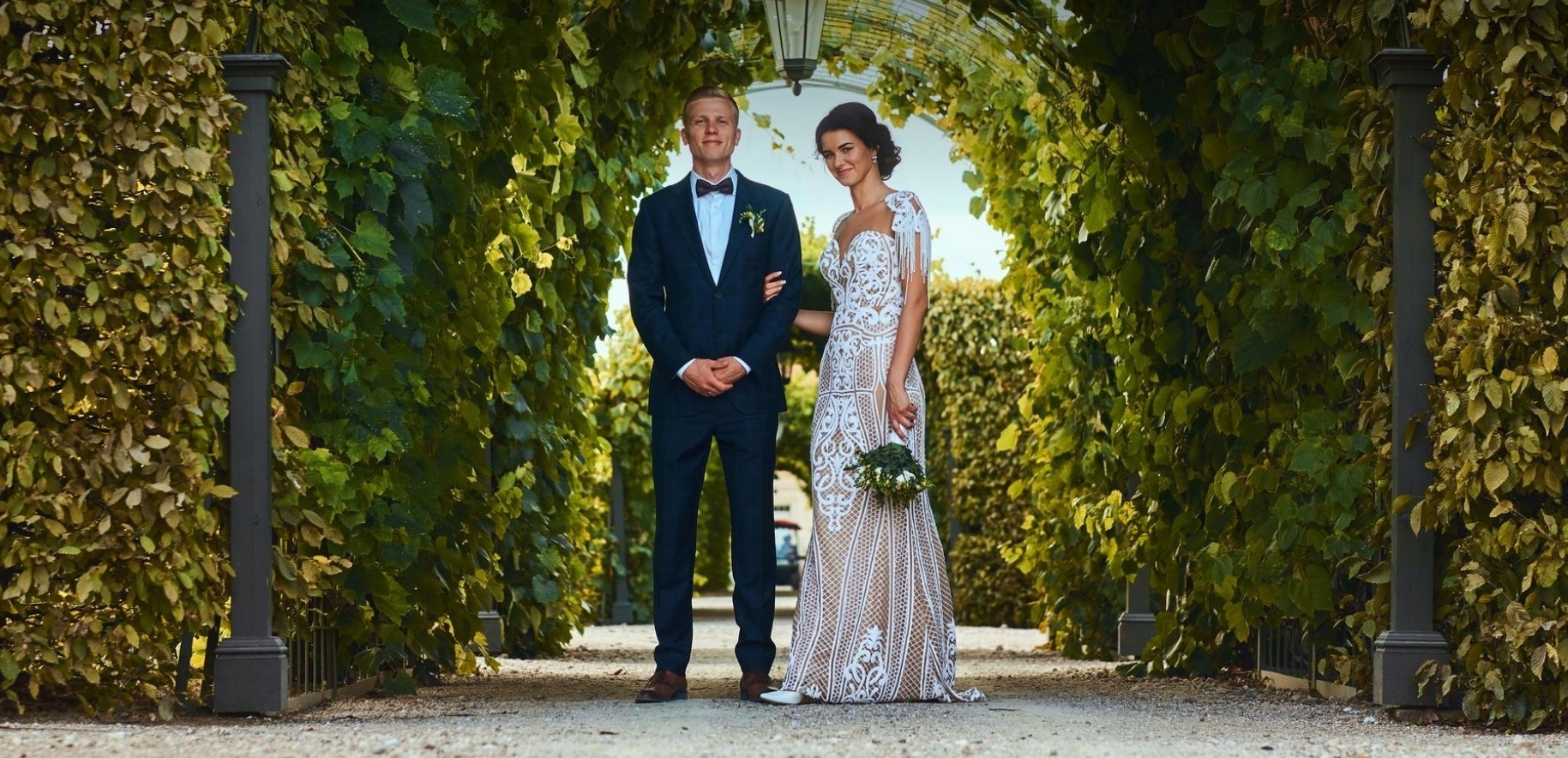 Bride and groom in a lush garden archway